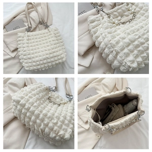 Detail van witte bubbeltextuur tas met parelhandvat en ruime opbergruimte binnenin