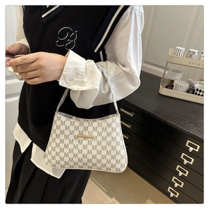 Detail of cream bucket bag with M-letter prints and a gold metal bar accent