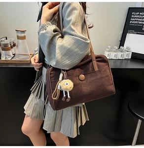 Detail of vintage brown suede shoulder bag with decorative ring and plush keychain