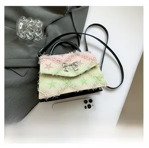 Détail du sac en toile avec motif d'étoiles colorées, bords effilochés et nœud métallique