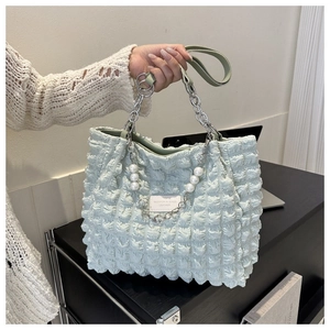 Detail van de mintgroene geplooide shopper met parels en een metalen kettingriem
