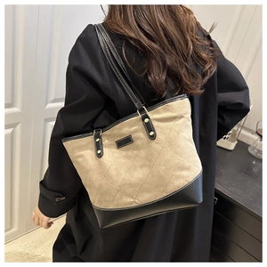 Gesteppte beige Canvas-Tragetasche mit schwarzen Lederdetails getragen in Innenräumen