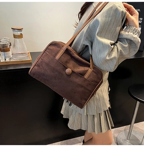 Close-up of retro brown suede shoulder bag featuring a front pocket and contrast strap