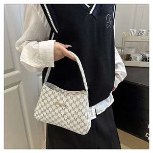 Detail of white bucket bag featuring grey M-pattern print and gold metal bar accent
