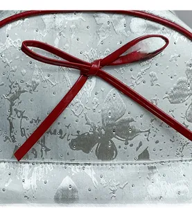 Close-up of silver jacquard fabric with beaded texture and red leather bow detail