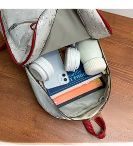 Spacious interior of silver bow backpack with tablet, headphones, and travel essentials