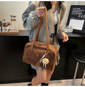 Détail d'un sac cabas vintage en daim marron foncé avec un porte-clé en peluche œil