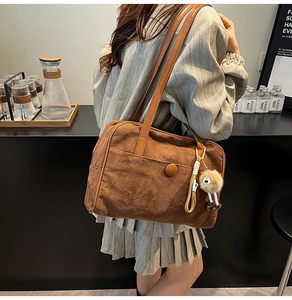 Detail of brown suede shoulder bag with plush charm and slim leather strap