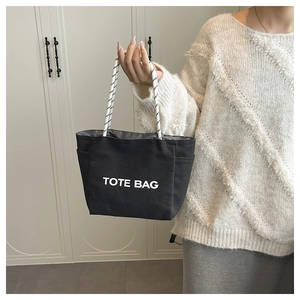 Detail of black canvas tote bag with side pockets and white spiral texture handles