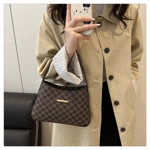 Macro shot of brown retro monogram shoulder bag with gold hardware on trench coat