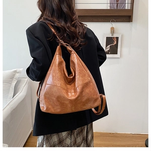 Brown vintage faux leather backpack on a model with black suit and plaid skirt