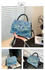 Detail of denim tote bag with star patterns, frayed edges and silver bow buckle