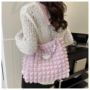 Detail van lichtroze popcorntextuur shopper met parelketting en metalen riem