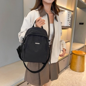 Detailansicht des schwarzen Nylon-Rucksacks mit Metall-Logo und Reißverschlussstruktur