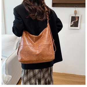 Brown vintage faux leather tote bag with oil wax finish shown on shoulder in lifestyle setting