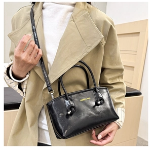 Detail of glossy black tote bag with fashion text and adjustable shoulder strap