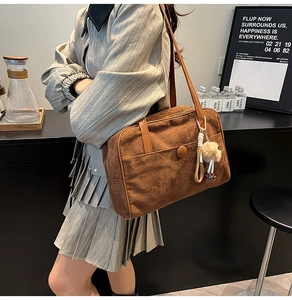 Detailed view of a brown suede shoulder bag with plush charm on a female model