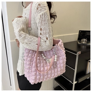 Roze getextureerde shopper met parelhanger en zilveren ketting op een bureau