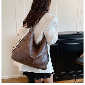 Detalle del gran bolso hobo marrón oscuro de cuero encerado retro en el hombro de una mujer