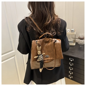 Macro detail of brown vintage PU leather backpack with rabbit charm and silver metal lock