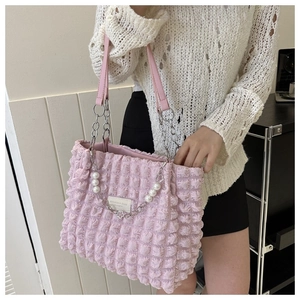 Detail van roze bubbelstructuur draagtas met elegante parelbanden en zilveren ketting