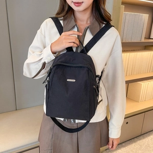 Detailansicht eines leichten schwarzen Nylon-Minirucksacks mit Metall-Logo und Reißverschluss
