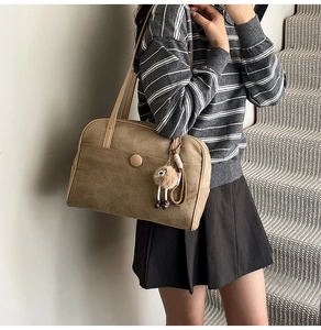 Detail of khaki suede tote bag with round decorative button and cute alpaca charm pendant