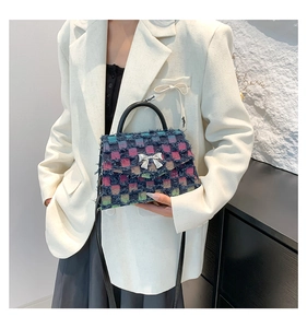 Detail view of denim plaid tweed small square bag with silver bow accent and top handle