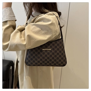 Detail of vintage monogram shoulder bag with metallic buckle on khaki trench coat