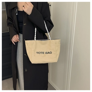 Detailed view of canvas tote bag with contrast polka dot rope handles and bold text