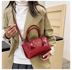Detailed view of a red patent leather tote bag with elegant handles and gold logo text