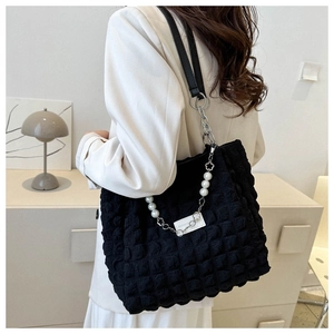 Detail van zwarte bubble tote tas met elegante parel- en bloemvormige kettingriem