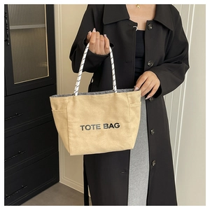 Detail of khaki canvas tote with letter print and striped rope handles on a model