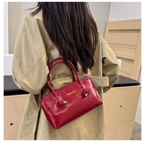 Detail of red glossy leather tote with gold logo and stylish knot hardware handle