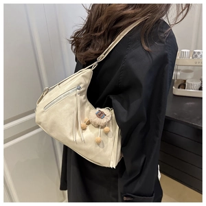 Detail of beige tote bag with silver hardware and a cute brown plush charm on the strap