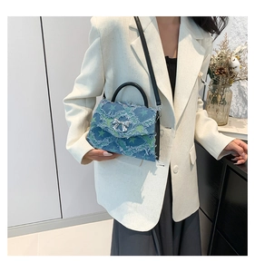 Blue denim crossbody bag featuring green star patterns and silver bow buckle on model