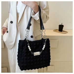 Detail van de zwarte tote bag met bubbeltextuur, parelketting en zilveren metalen hardware