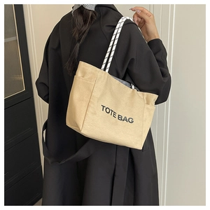 Detail of canvas tote bag showing textured fabric, side pocket, and woven rope handles