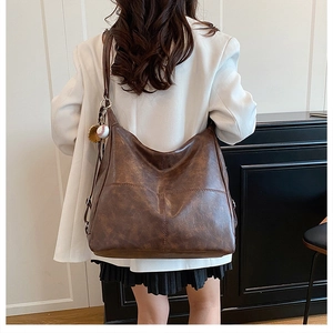 Brown vintage tote bag with baseball charm detail and textured leather stitching