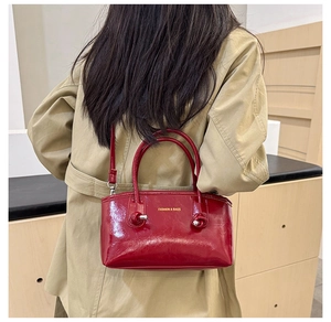 Model wearing red patent leather tote bag over a tan trench coat for a stylish street look