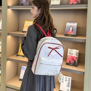 Detail showing white PU backpack with red trim, bow accent and butterfly patterns