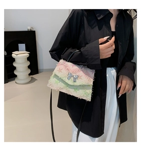 Detailed side view of gradient denim handbag with a silver bow clasp and frayed edges