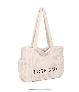 Detailed view of corduroy tote bag with side pocket and black TOTE BAG embroidery