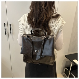 Close-up of dark brown PU leather texture and vintage oval metal twist lock on backpack