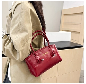 Detail of burgundy leather tote bag with gold lettering shown on a model