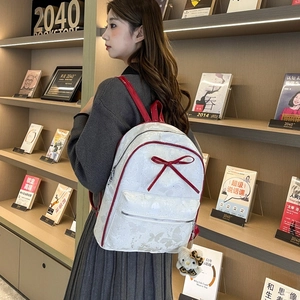 Detailed back view of a white PU leather backpack featuring a red bow and butterfly print