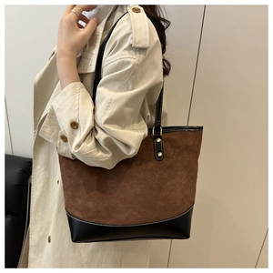 Detail of quilted brown suede and black leather stitching on a large tote bag