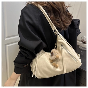 Detail of cream PU leather wavy underarm bag with silver zipper and plush charm