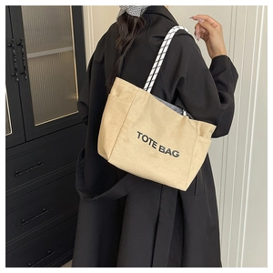 Detail of khaki canvas tote bag with black and white woven rope strap and side pocket
