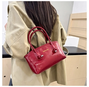 Close-up of stylish red glossy leather tote bag with elegant golden fashion lettering
